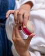 A child holding a Wobbel Candy Macaron in their hands. The Macaron is natural PEFC certified maple and beech wood, and shows the smooth finish and wood grain texture, with a pink "filling". The Wobbel Candy Macaron are perfect for stacking, rolling, slidi