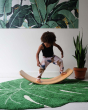 Child balancing on a Wobbel Original Bamboo balance board in a white and green room
