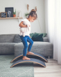 Girl walking on two upturned Wobbel Pro Felt balance boards in front of a grey sofa
