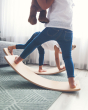 Two children balancing on Wobbel Starter balance boards with felt on a living room carpet