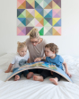Woman and two children reading a book on a Wobbel XL felted balance board on a bed