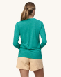 An adult wearing the Patagonia Women's Long-Sleeved Capilene Cool Daily Graphic Shirt - Channel Islands / Subtidal Blue X-Dye, , and light yellow shorts