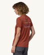 An adult wearing the Patagonia Women's Capilene Cool Daily Graphic Shirt. This photo shows the fit of the t-shirt from the side, on a cream background