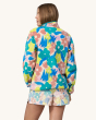 An adult showing the back of the Patagonia Women's Lightweight Synchilla Snap-T Fleece Pullover - Channeling Spring / Natural. This fleece has bright, colourful flower print details in pink, green, yellow and blue. The adult is wearing colourful, flowery 