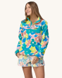 An adult wearing the Patagonia Women's Lightweight Synchilla Snap-T Fleece Pullover - Channeling Spring / Natural, with colourful shorts on a cream background. This fleece has bright, colourful flower print details in pink, green, yellow and blue.