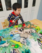 Close up of young boy playing with wooden toy animals on the Wonder Cloths organic cotton into the jungle play cloth