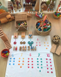 Wonder Cloths first numbers learning cloth laid out on a wooden floor next to baskets of madala pieces and wooden toys
