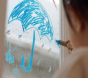 Close up of a child drawing an umbrella with a Kitpas window crayon on a rainy window
