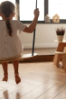 Girl sat on the babai eco-friendly black wooden swing in a bright living room