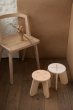 Pink and natural Babai childrens stools on a wooden floor in front of a wooden chair
