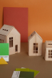 Small, medium and large babai dollhouses on a brown table in front of an orange wall