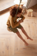 Child swinging on a Babai eco-friendly wooden rope swing in a wooden living room