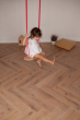 Child swinging on the Babai eco-friendly rope swing set above a wooden living room floor