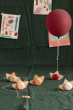 Babai sustainable wooden pull and go ship toys spread out on a green sheet below a red balloon