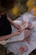 Close up of a young boy holding the Babai sustainable lacing toy set on a blue picnic blanket