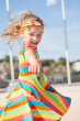 Child spinning around wearing the Frugi Rainbow Stripe Spring Skater Dress with a matching headband