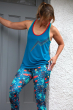 Woman stood in front of a grey door wearing the Frugi organic cotton blue lyra vest top