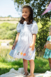 child standing outside wearing the  Frugi Beach Hut Blue and white Stripe Cassie Collared Dress