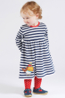 a little girl wearing frugi dea dress in indigo and white stripe print and adorable robin appliqué