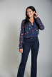 Woman wearing Frugi's georgette blouse in indigo with northern lights print and jeans on a grey background