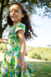 Side view of a child wearing the Frugi Hedgerow print Spring Skater Dress