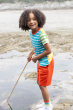 A child playing in a rock pool, with a net at the beach, and wearing the Frugi Children's Organic Cotton Hotchpotch Applique T-Shirt - Lobster and orange shorts