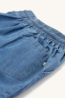 A closer view of the back pocket and material of the Frugi Organic Cubert Chambray Denim Shorts, on a cream background