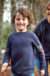Boy running in a park wearing the Frugi organic cotton lightning easy on jumper 