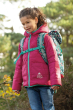 Girl stood in front of some bushes wearing the Frugi recycled toasty trail jacket in the mountain flora colour