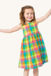 A child smiling and posing with their arms open wide, wearing the Frugi Organic Arya Summer Dress - Summertime Check, on a cream background
