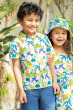 Two children happily smiling in the sun outside, stood in front of leafy green plants. The child on the left wears Frugi Organic Harvey Hawaiian Shirt - Jaguar Jungle and Frugi Denim Cotton Shorts