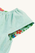 A closer look at the Frugi Children's Organic Cotton Lowen Reversible Dress - Tropical Birds / Spring Dobby, showing the reversible flowery pattern inside