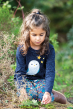 Frugi long sleeve organic cotton nila nepp t-shirt worn by a girl playing in the grass with leaves