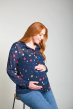 Pregnant woman wearing the Georgette Maternity blouse by Frugi in Northern Light pritn holding baby bump on a grey background