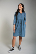 Woman wearing Frugi Mila chambray long sleeve shirt dress with navy embroidered flowers on the shoulders with trainers looking up