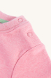 The shoulder popper fastenings on the Frugi Organic Little Creature Applique T-Shirt - Pink Marl / Macaw. On a cream background