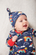 Baby laying on a fluffy white carpet wearing the Frugi eco-friendly organic rainbow sky clothing gift set