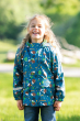 Girl stood in a field wearing the Frugi eco-friendly recycled polyester national trust puddle buster jacket