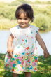 Child outdoors wearing the Frugi Soft White Flowers Elowen Dress