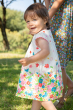 Side view of a child wearing the Frugi Soft White Flowers Elowen Dress 