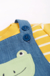 Close up of the extendable button closure on the straps of the Frugi The National Trust Lincoln Chambray Frog Dungaree Outfit pictured on a plain white background