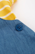 Close up of the button on the side of the Frugi The National Trust Lincoln Chambray Frog Dungaree Outfit pictured on a plain white background