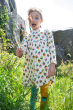 Child wearing Frugi Children's Bumblebee Acorn Organic Cotton Norah Tights outside on a grassy path with rocks behind.