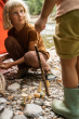 Girl crouched down on some sandy pebbles playing with the Grapat plastic-free wooden wonders toy set