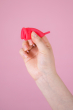 Hey Girls Large red Silicone Menstrual Cup folded in someone's hand on a pink background