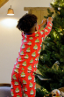 Child wearing Maxomorra Swedish Santa Pyjamas, adding Christmas decorations to a Christmas tree