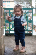 Young girl walking in front of a blue railing wearing the Meyadey city life short sleeve top under some denim dungarees