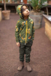 Meyadey Marvellous Macaw, organic, zipped hoodie in rich green with macaw and leaves repeat print. Worn by a young person with dark green trousers