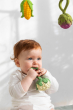 A baby cluting onto and chewing the Oli & Carol Cauliflower Rattle Teether