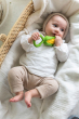 baby lying down in a changing basket clutching onto the Oli & Carol Corn Rattle Teether 